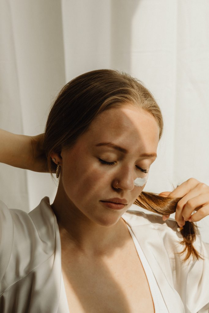 woman with eyes closed holding ponytail