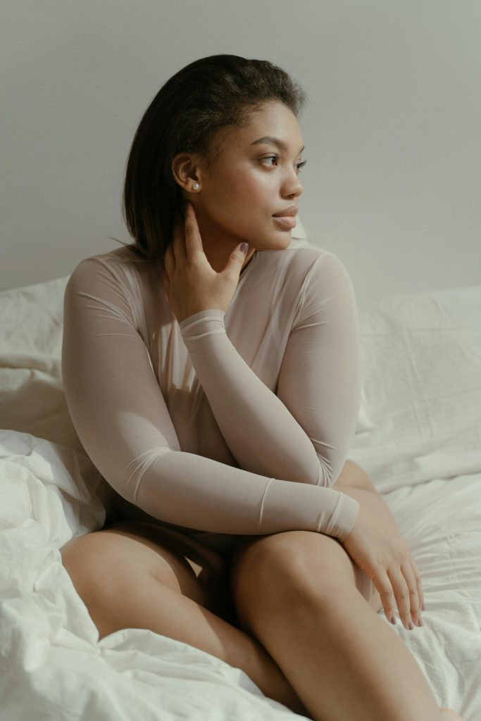 woman in beige top sitting on bed