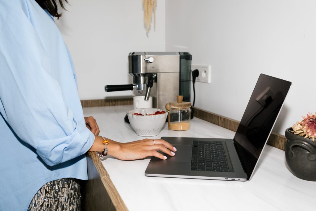 woman using laptop on kitchen worktop