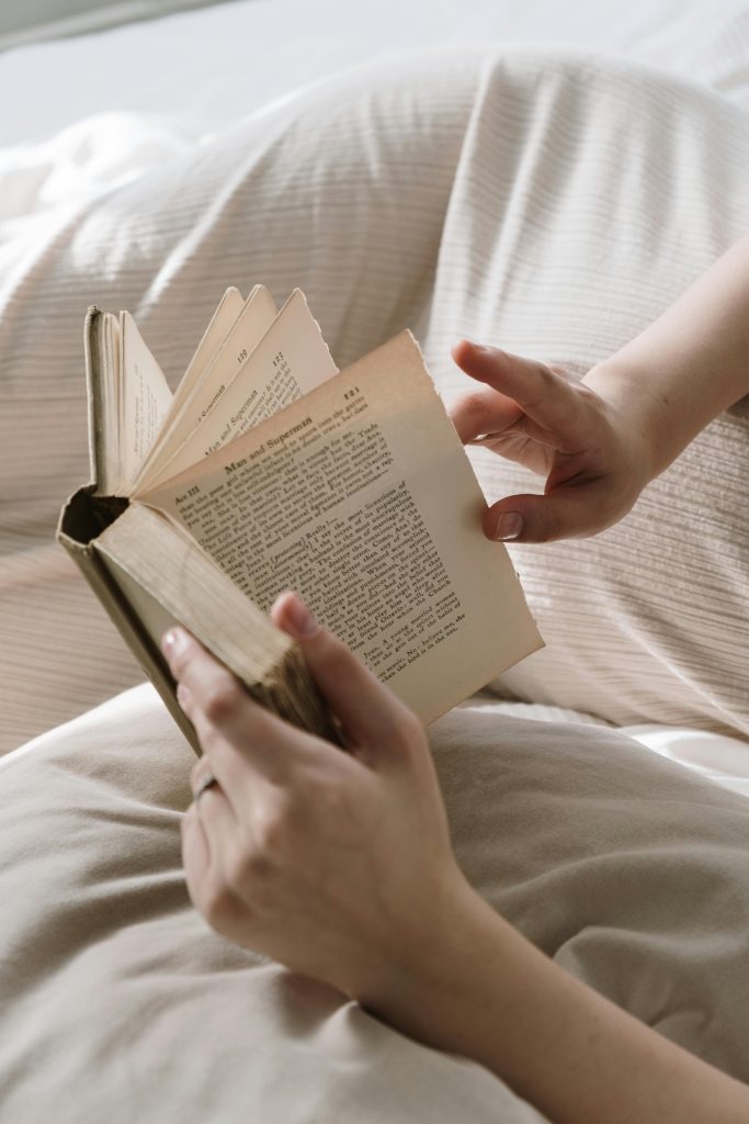 woman reading book in bed