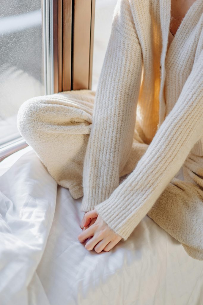 low energy habits, woman in cream knitted jumper sitting on bed
